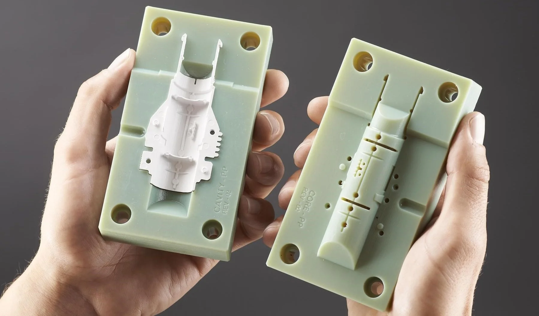 Hands holding a green plastic injection mold with a white molded part, illustrating the benefits of precision and efficiency in injection molding manufacturing.