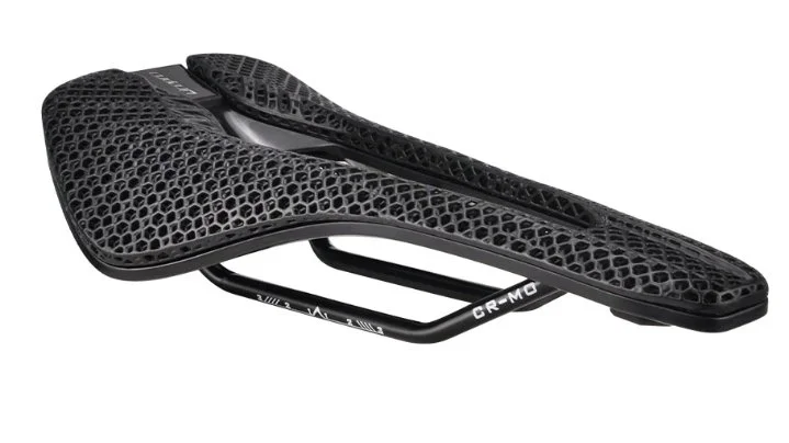 En svart cykelsadel med bikakemönster och kromliknande skenor.