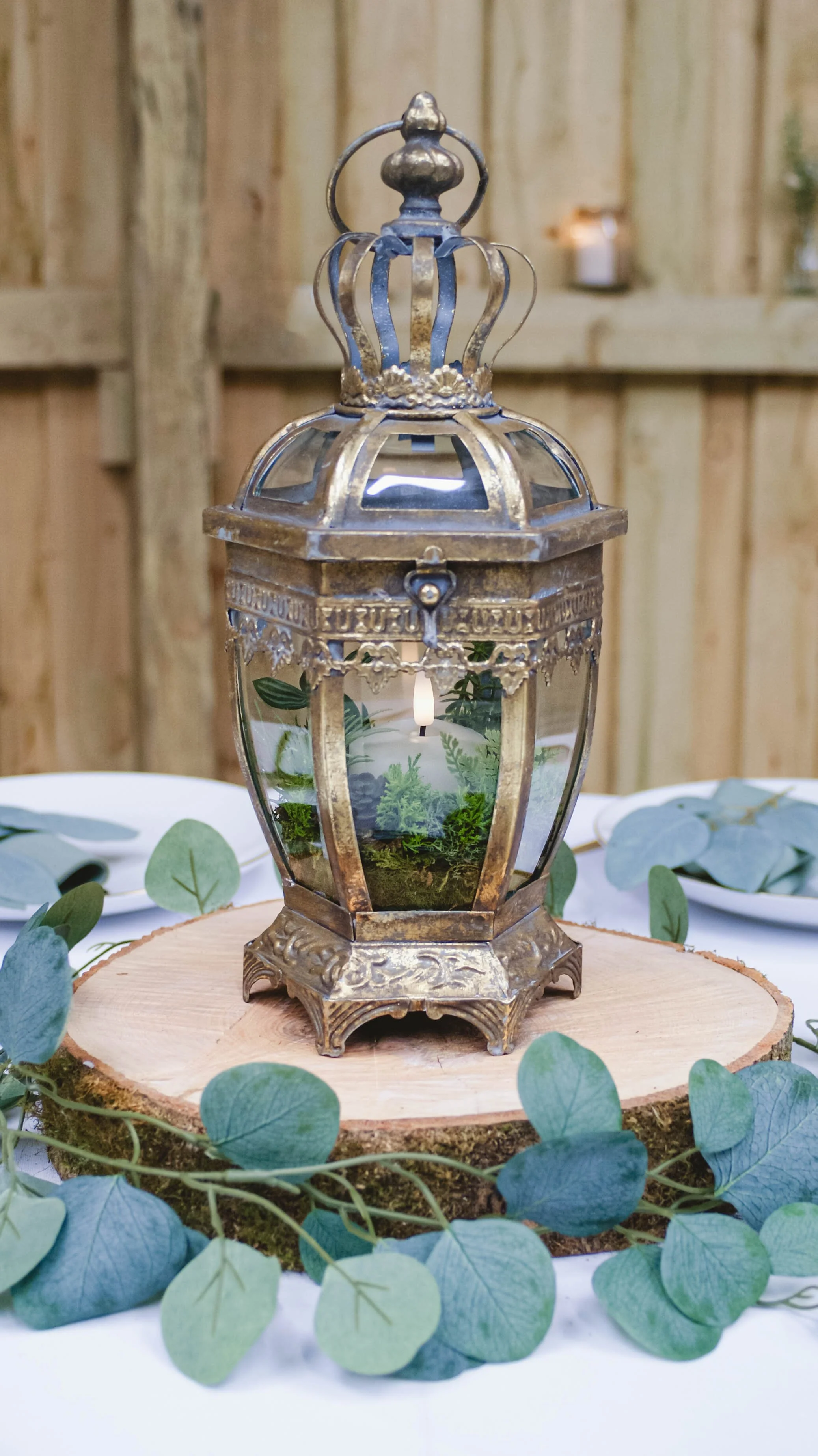Log slice centrepiece with gold lantern on top with eucalyptus.jpg