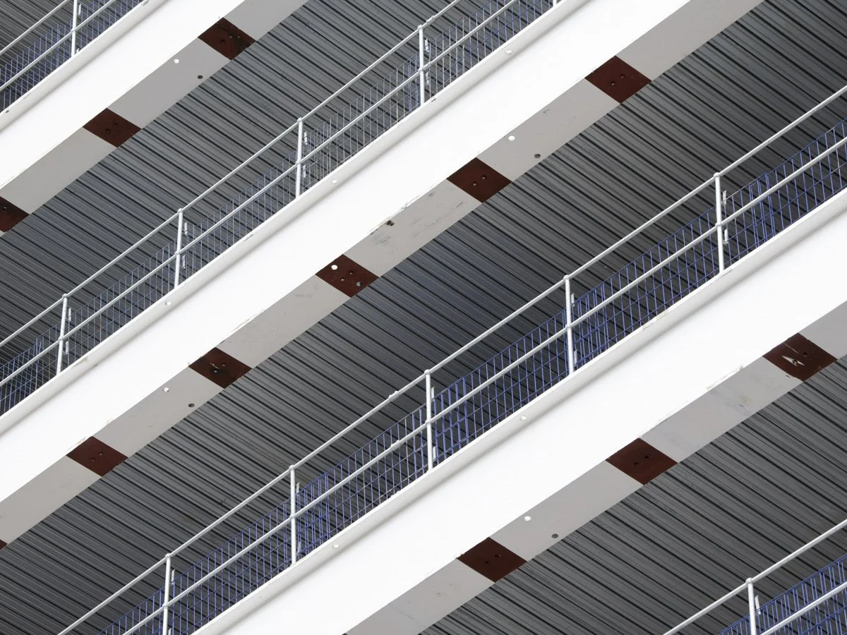 Close-up of escalator stairs with metal railings and striped pattern in gray, black, white, and brown colors.
