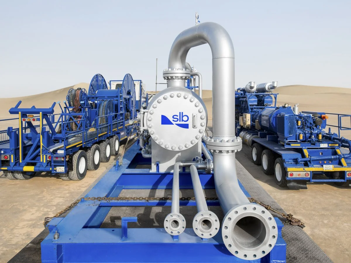A large industrial pump system mounted on a blue trailer with multiple pipes, hoses, and engines, situated in a desert landscape.