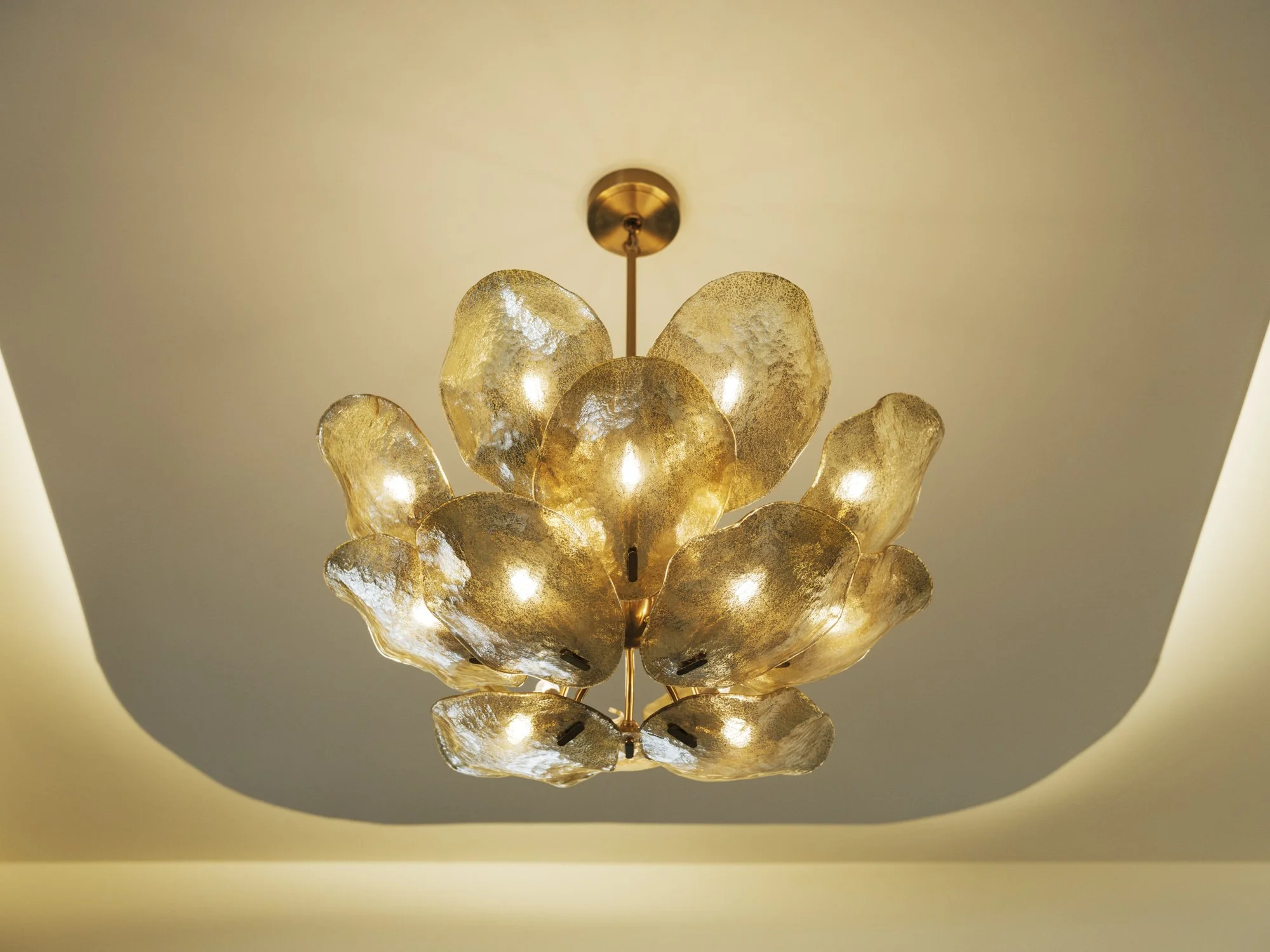 Elegant chandelier with gold leaf-like petal-shaped glass shades hanging from the ceiling