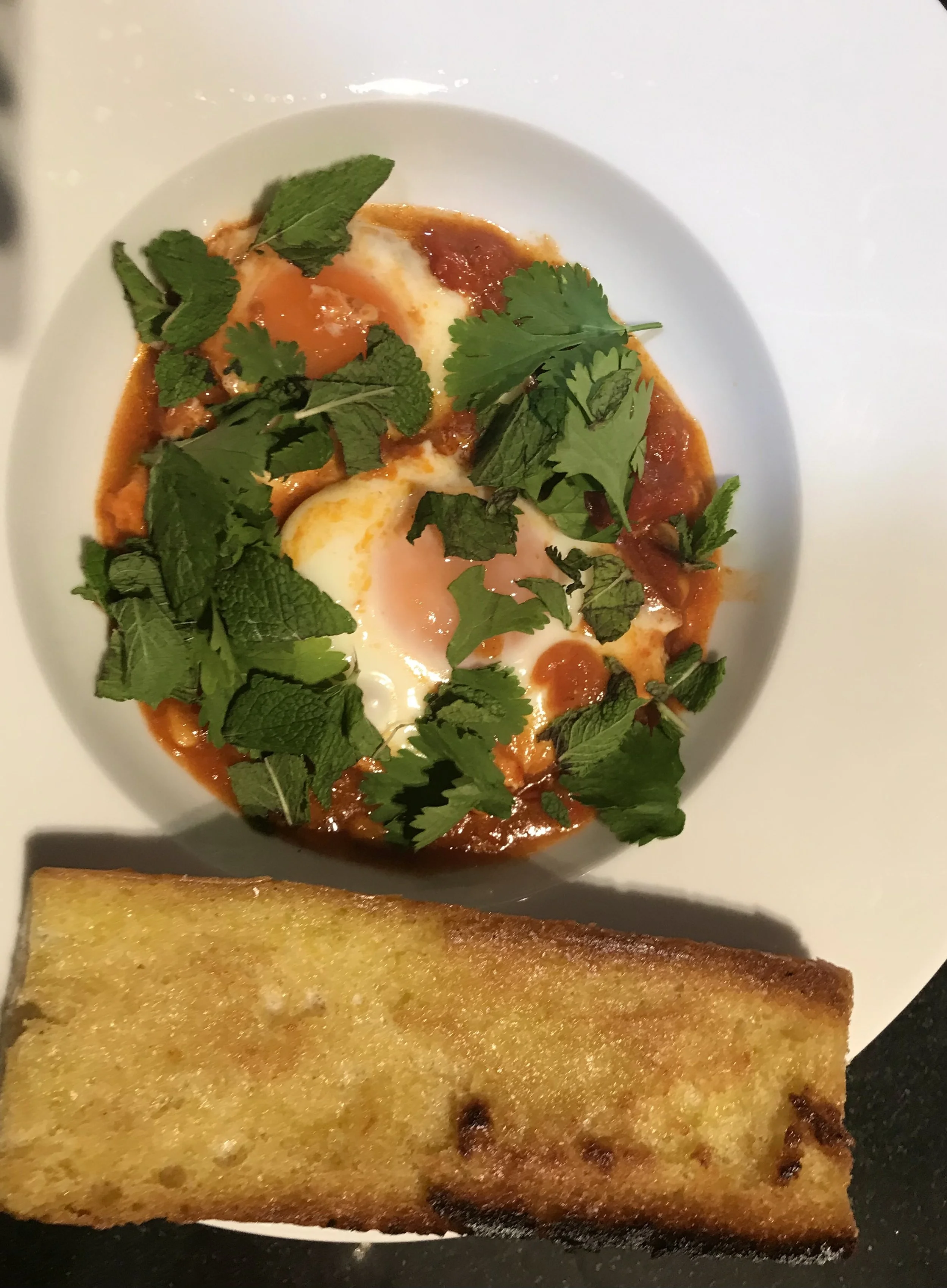 Egg shakshuka with herbs and a piece of grilled bread
