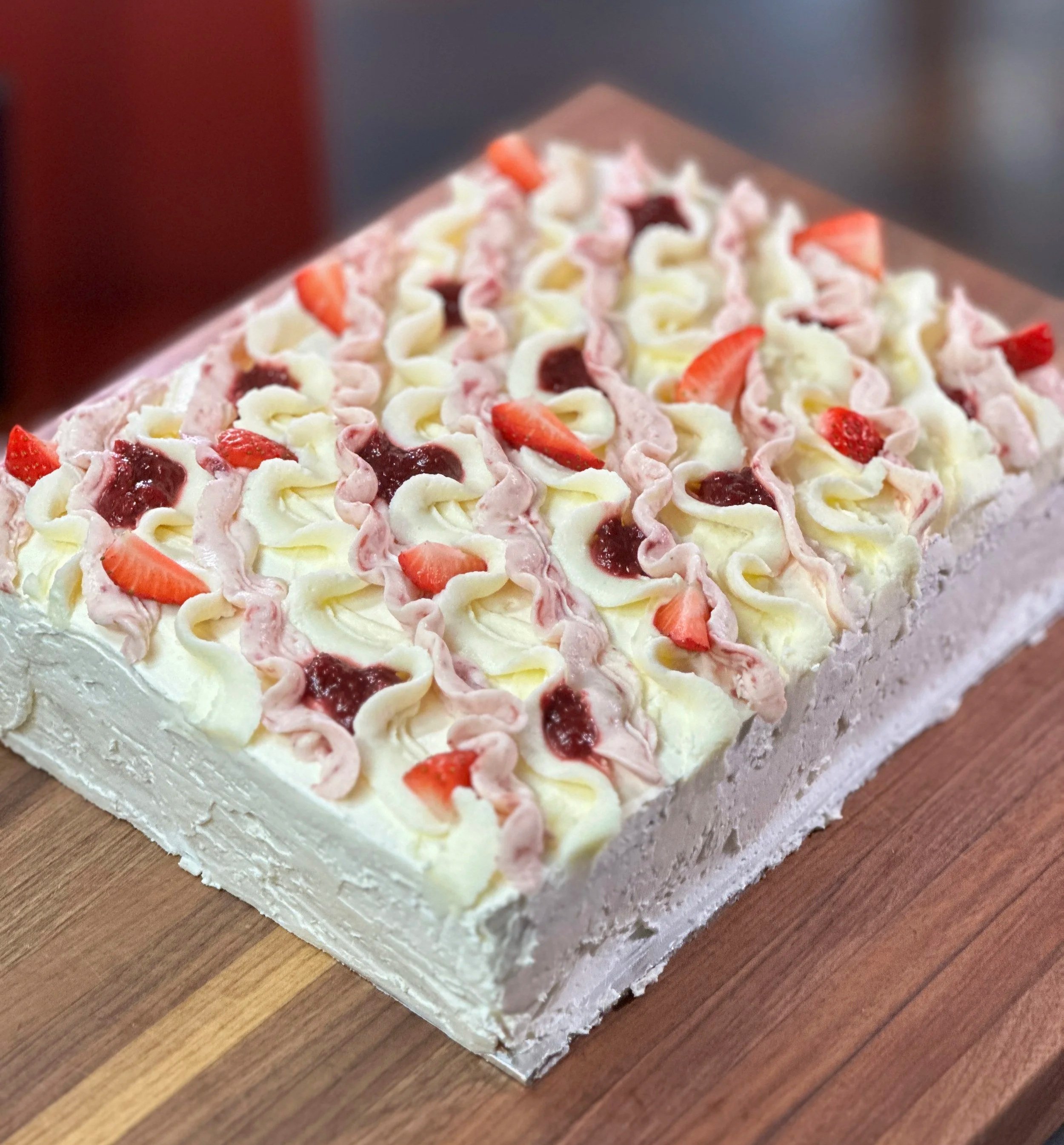 Strawberries and cream cake on a wooden cutting board.