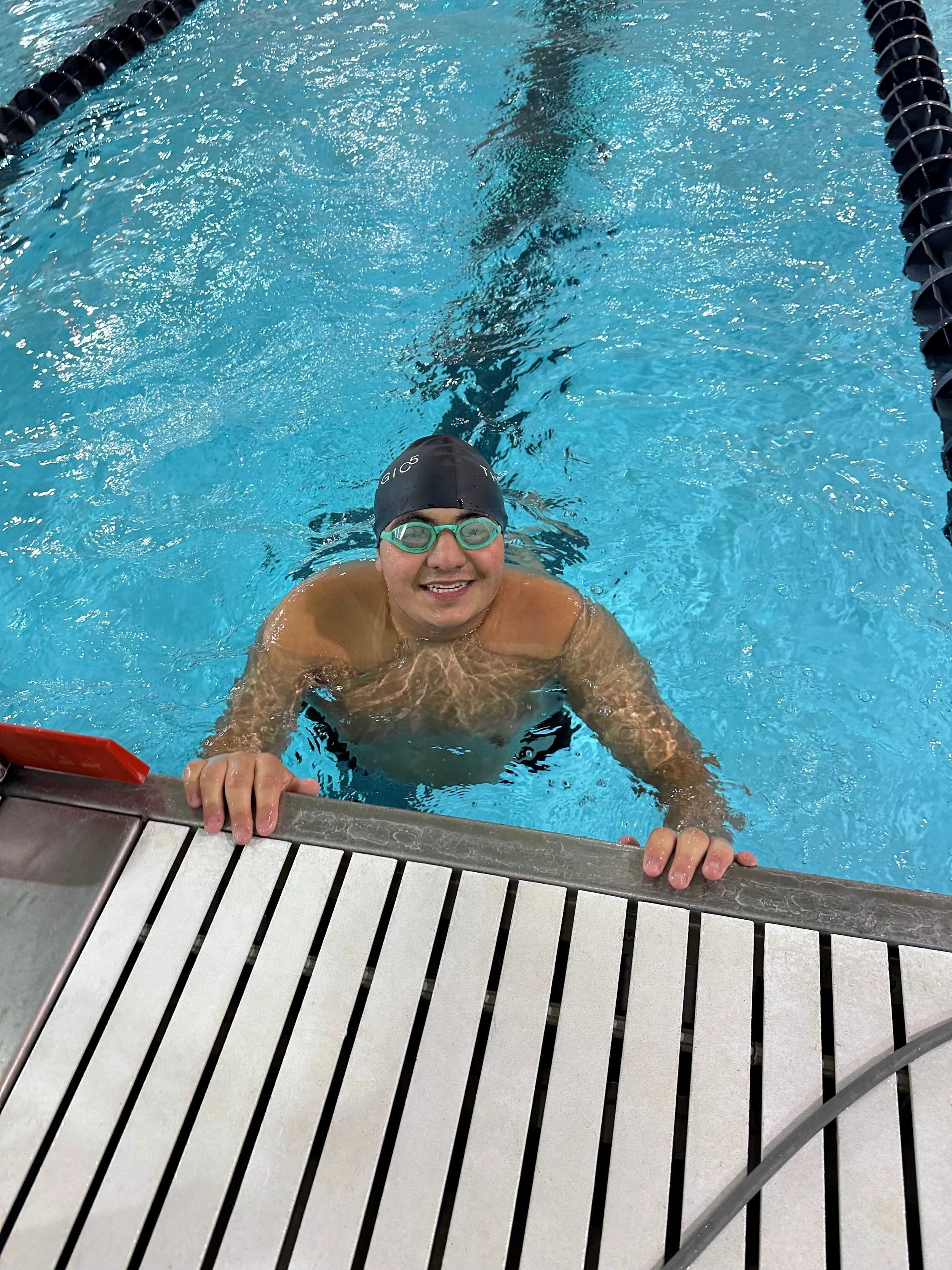 Teenaget boy, Tommy, who is the subject of this story, holding onto the edge of a pool smiling.