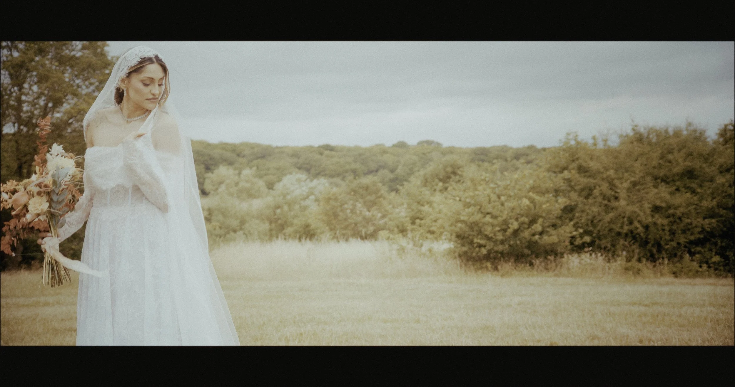 Bride in a white dress with long leice veil standing in Epping Forest on her Wedding Day