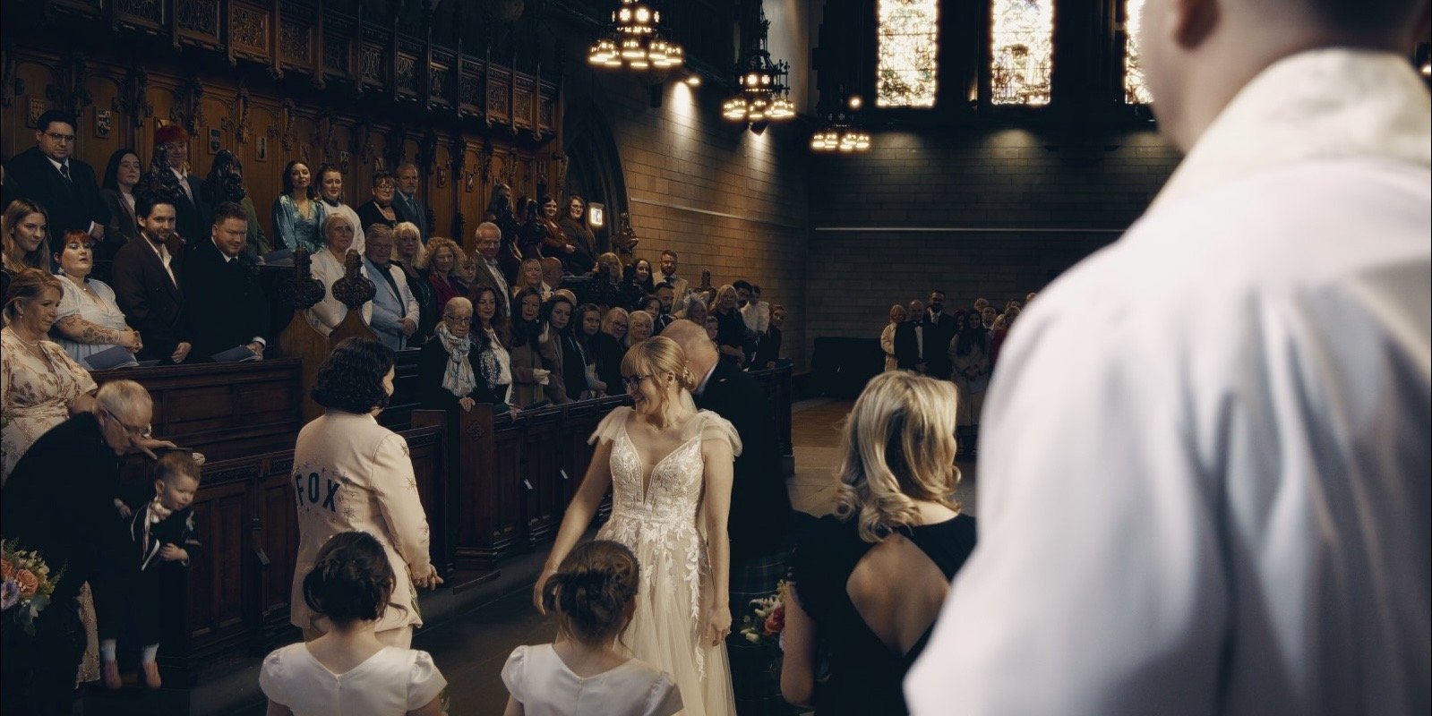 One Bride in white dress and another Bride in a pink suite, standing in a church before their Wedding Ceremony 