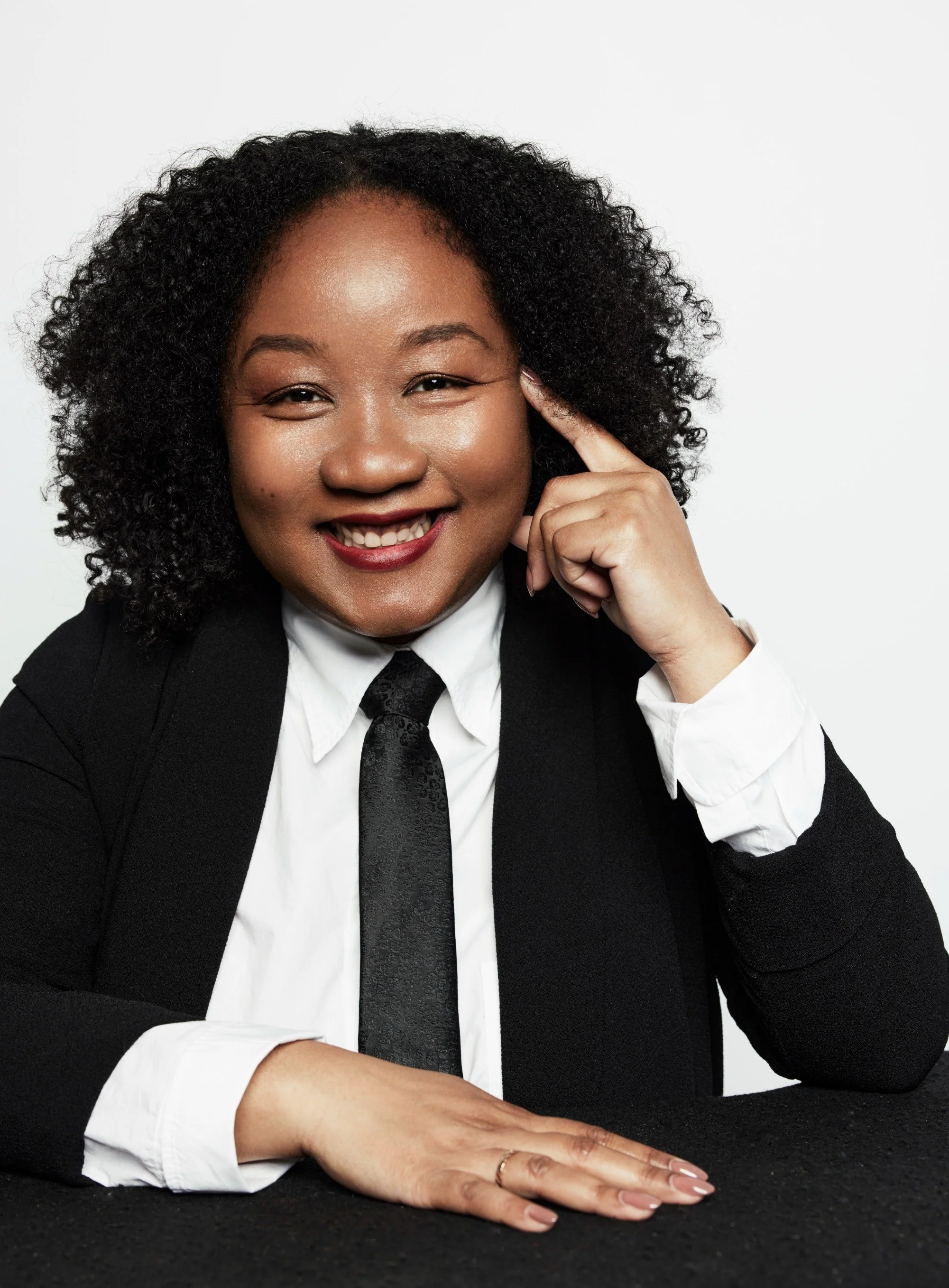 Portrait of Coko Galore in a black suit and tie