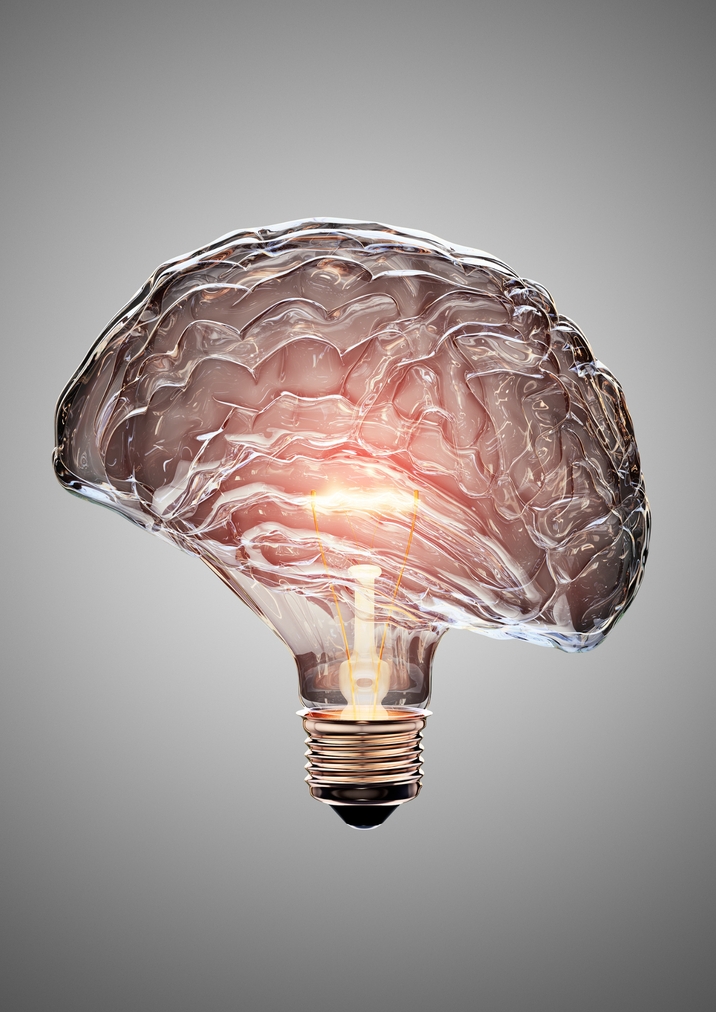 A glass light bulb shaped like a human brain, with glowing orange light inside, set against a grey background.