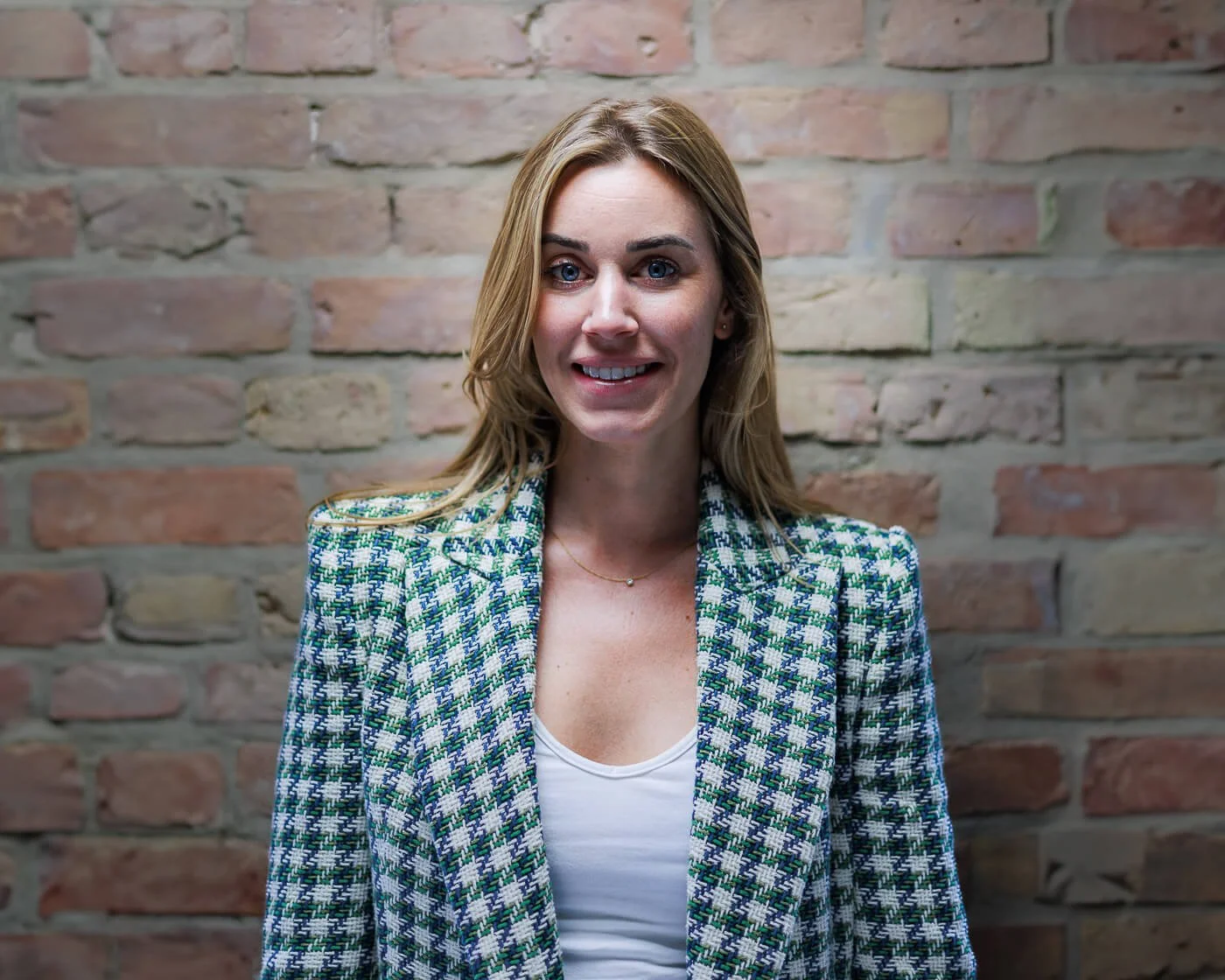 Headshot Berlin: Beatrice Frensel im karierten Blazer lächelnd vor einer Backsteinwand