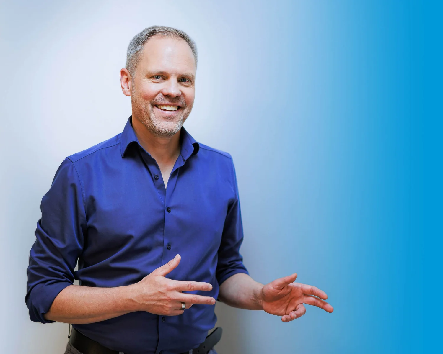 Business Portrait Berlin: Thomas Dürst im blauen Hemd mit erklärender Geste im Gespräch