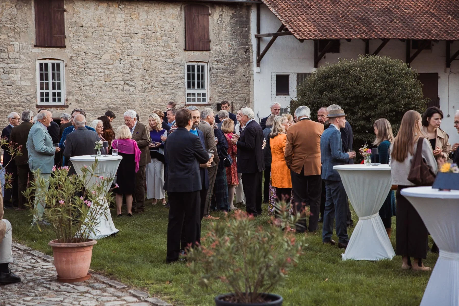 Gäste der Cocktail Hour auf der Wiese vor den historischen Wirtschaftsgebäuden
