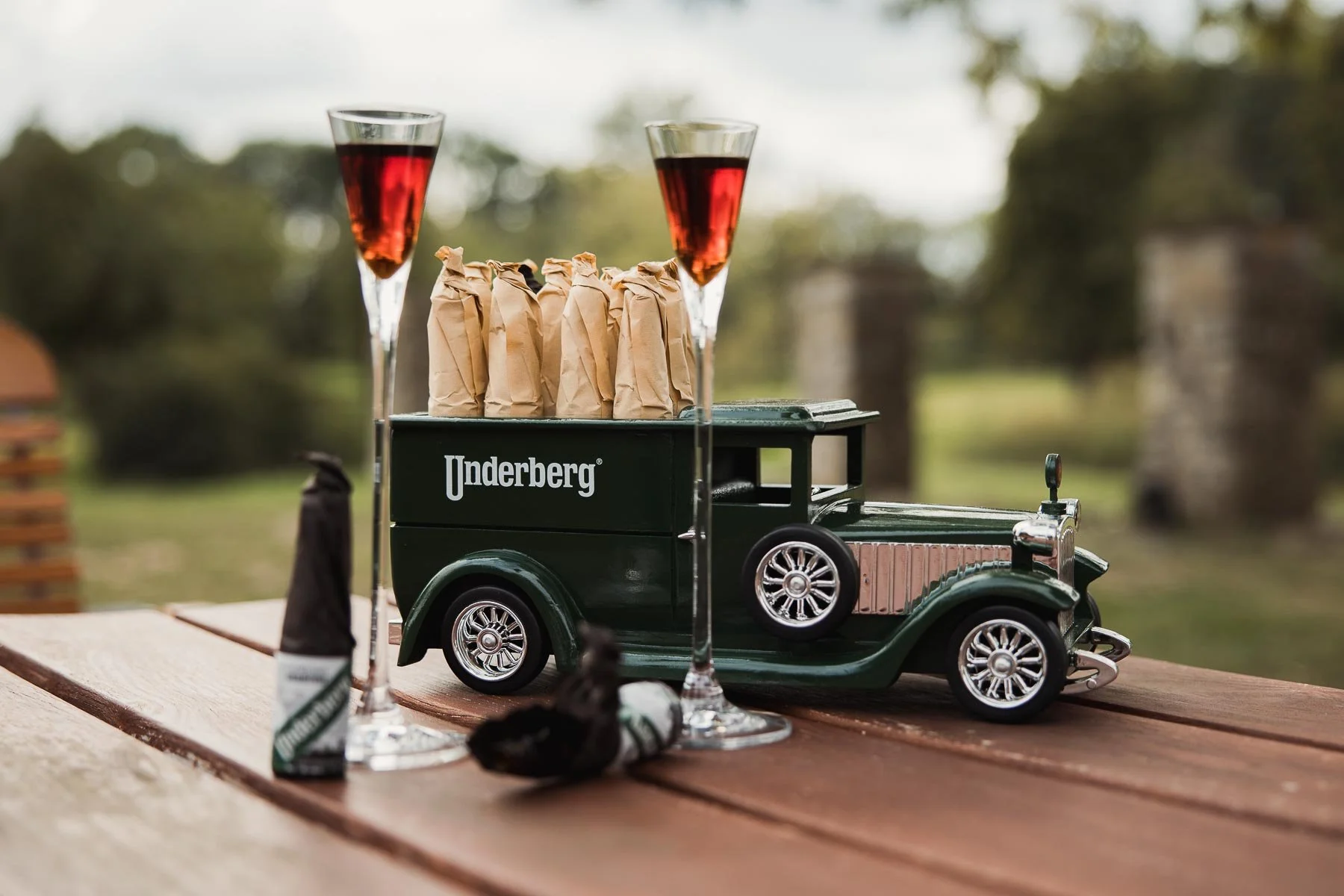 Underberg-Modellauto mit Kräuterbitter und Gläsern auf einem Gartentisch