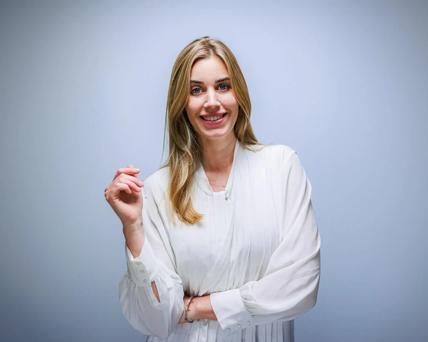 Businessfotograf Berlin: Businessporträt von Beatrice Frensel in weißer Bluse mit verschränkten Armen vor grauem Studiohintergrund