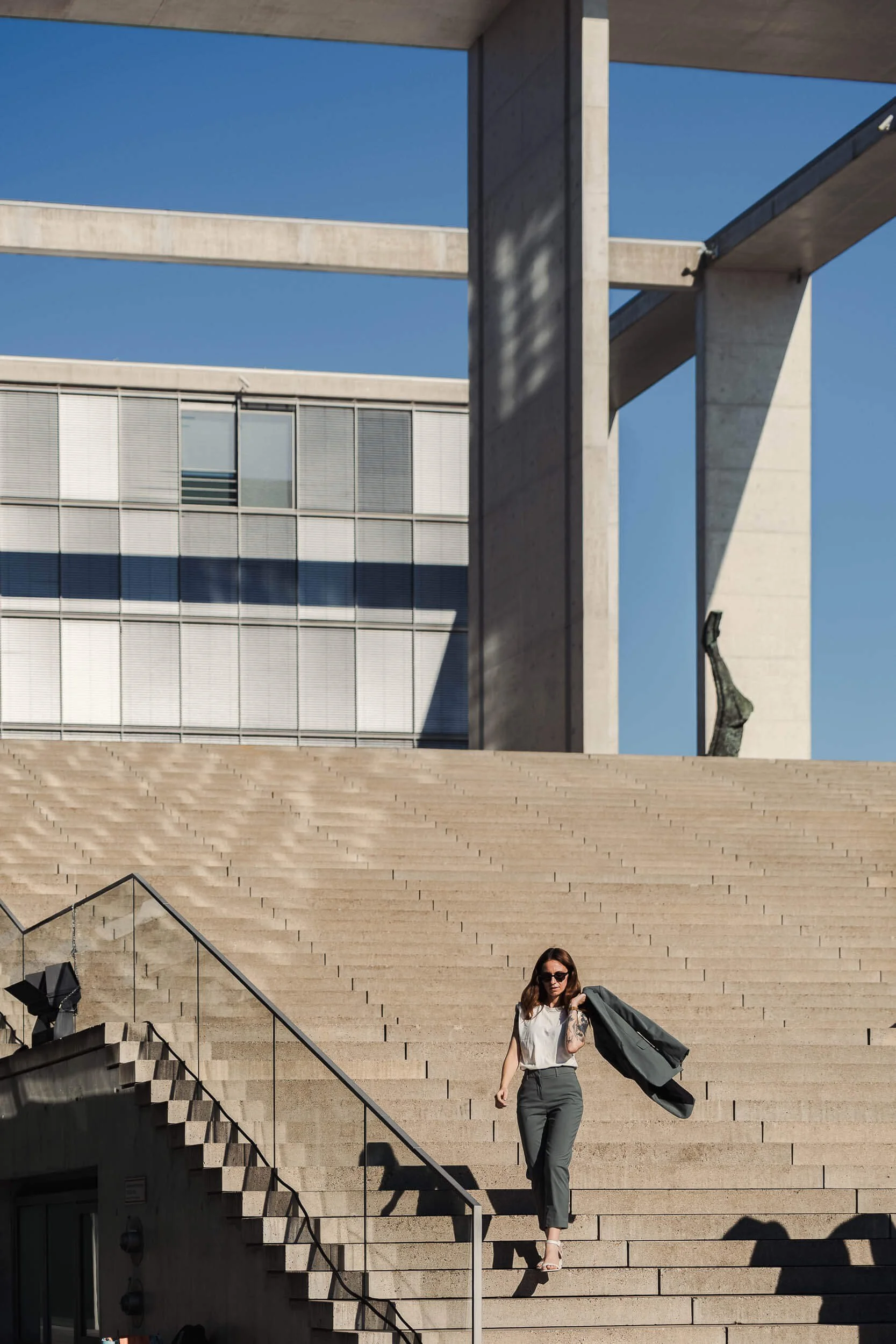 Architekturfotograf Berlin: Frau auf der Freitreppe am Band des Bundes im Spreebogen vor Sichtbetonarchitektur