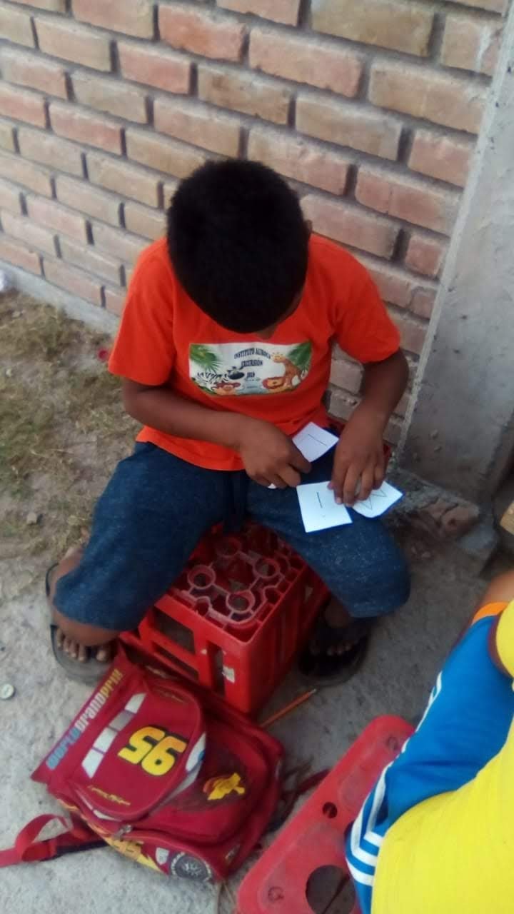Niño tomando clases sobre una caja de refrescos.jpeg