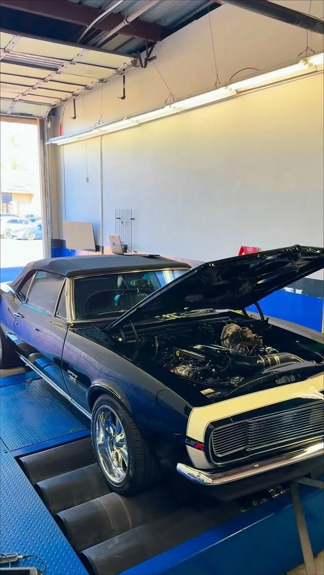 Classic Chevrolet Camaro with open hood on the shop dynamometer