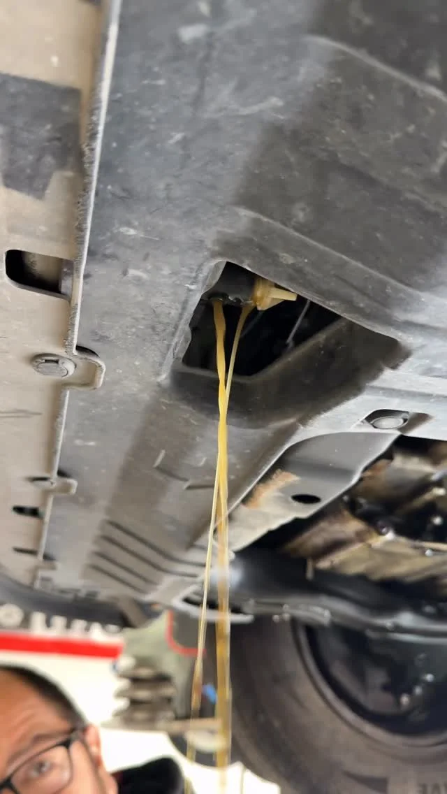 Discolored fluid draining beneath a vehicle in the shop