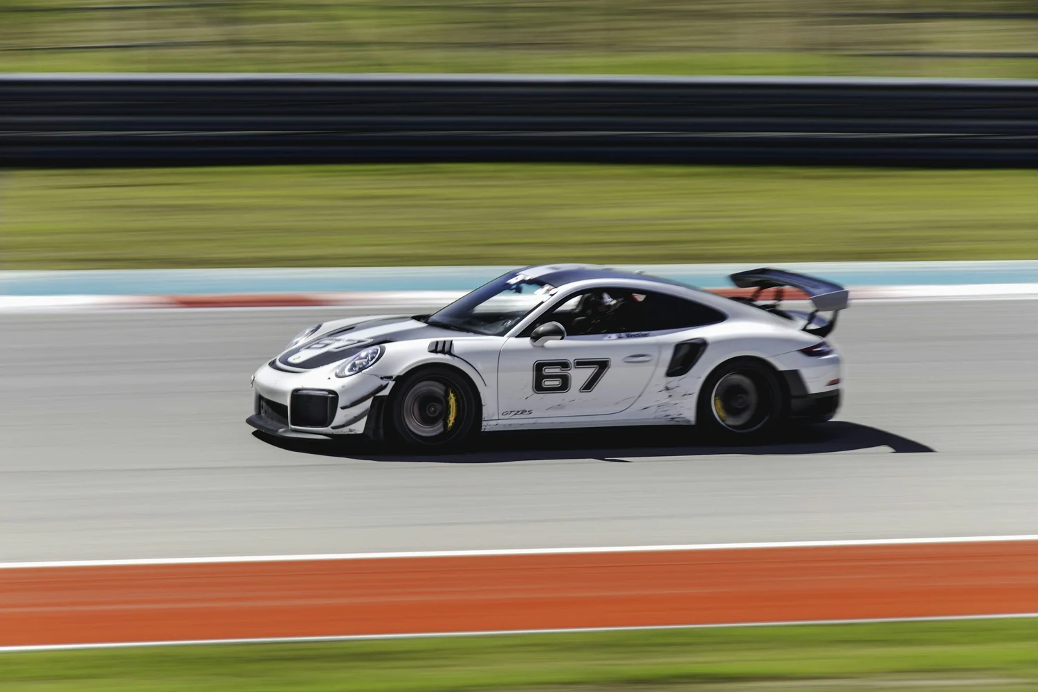 Porsche track car with a rear wing driving on a road course