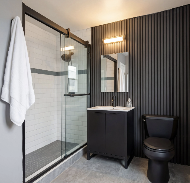 Modern condo bathroom renovation with glass shower and black fixtures in NYC.