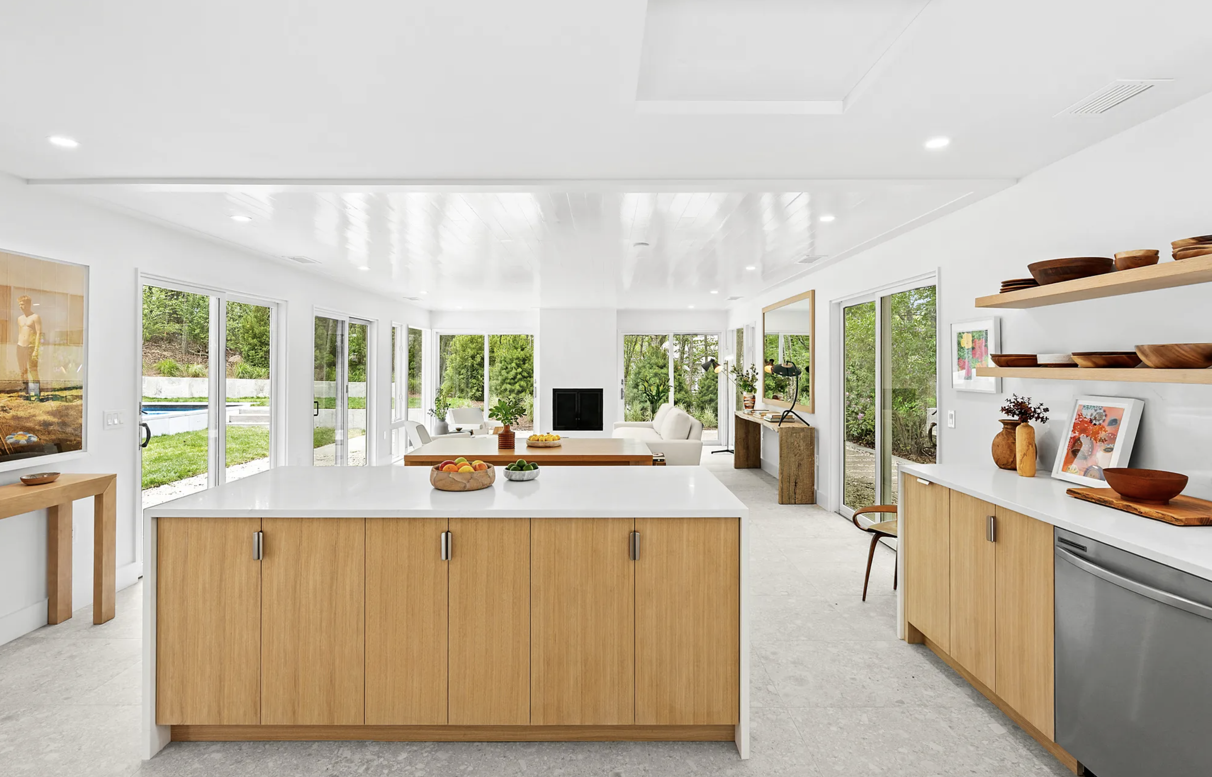 Open kitchen with central island, light wood cabinetry, and expansive windows overlooking the landscape