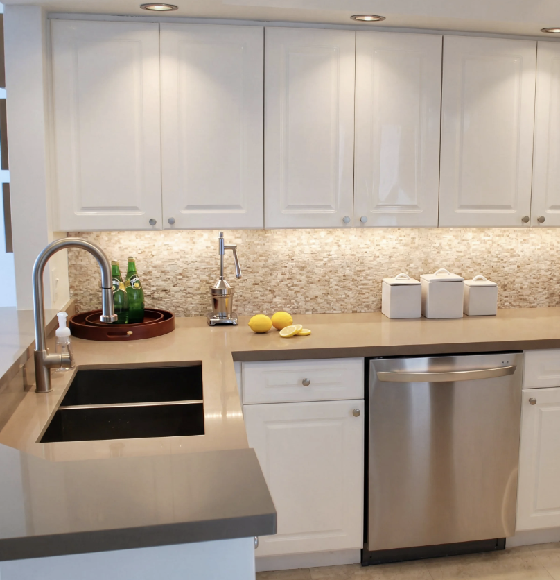 Updated Miami Beach condo kitchen with white cabinetry and stainless steel appliances.
