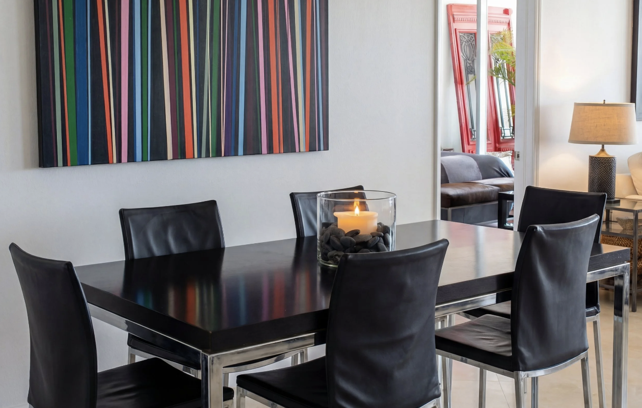 Modern Miami condo dining area with black table and colorful artwork.