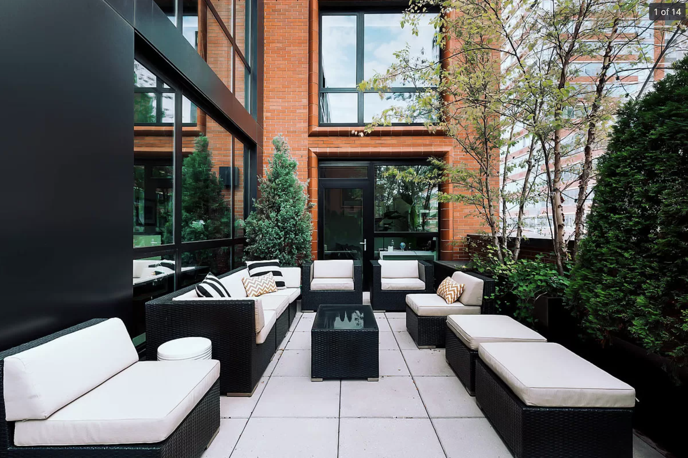 Urban outdoor terrace with modern seating, integrated planters, and brick building backdrop
