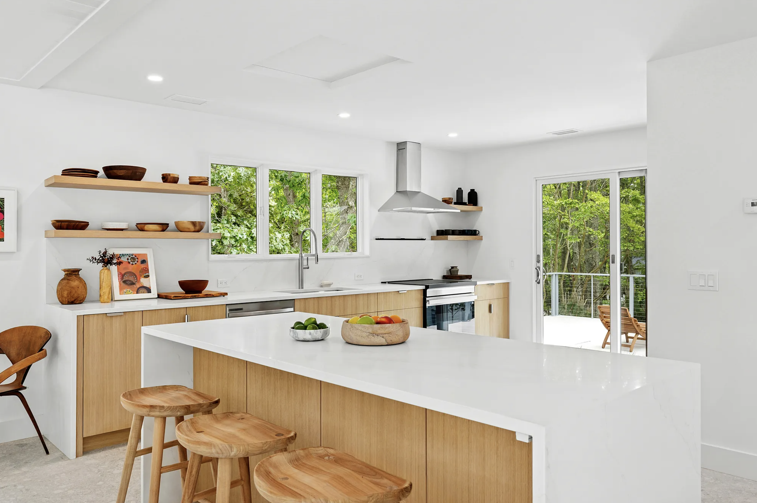 Kitchen island with light wood cabinetry, white surface, and seating, set within a light-filled interior