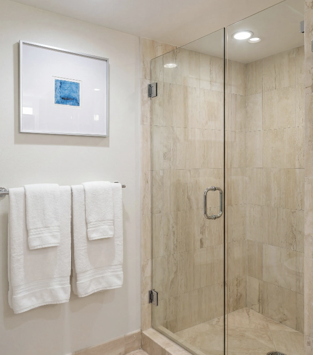 Contemporary condo bathroom with glass walk-in shower and beige tile walls.
