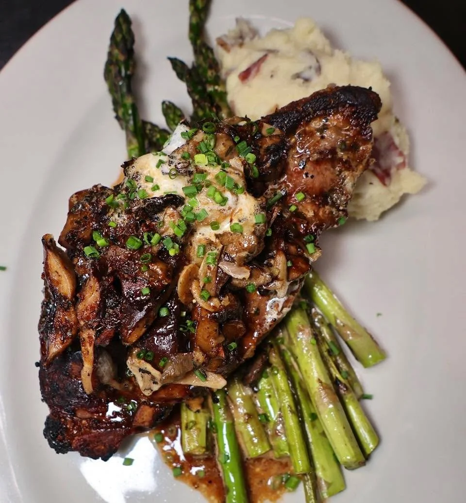 A plate built for Steak Night 🥩🍷

14oz Marinated Prime Shell Steak, grilled and finished with shallot compound butter. Served with roasted garlic mashed potatoes, wild mushrooms, and grilled local asparagus! This week only! 

#weekendmood #steaknig
