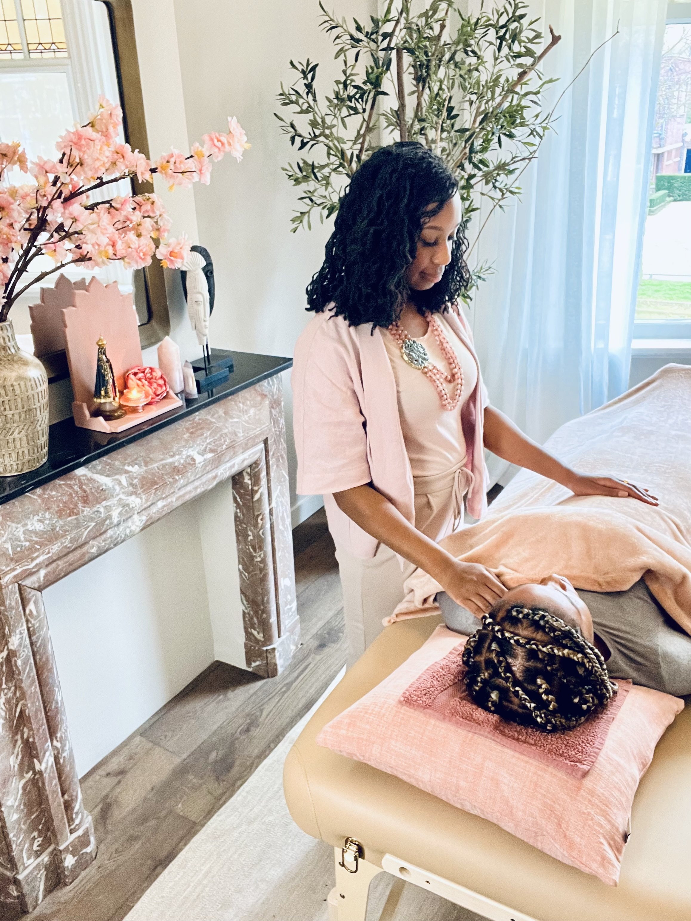 Een vrouw krijgt een energy healing op een tafel met een doek over haar lichaam, terwijl een paragnost negatieve energie verwijdert en haar aura reinigt.
