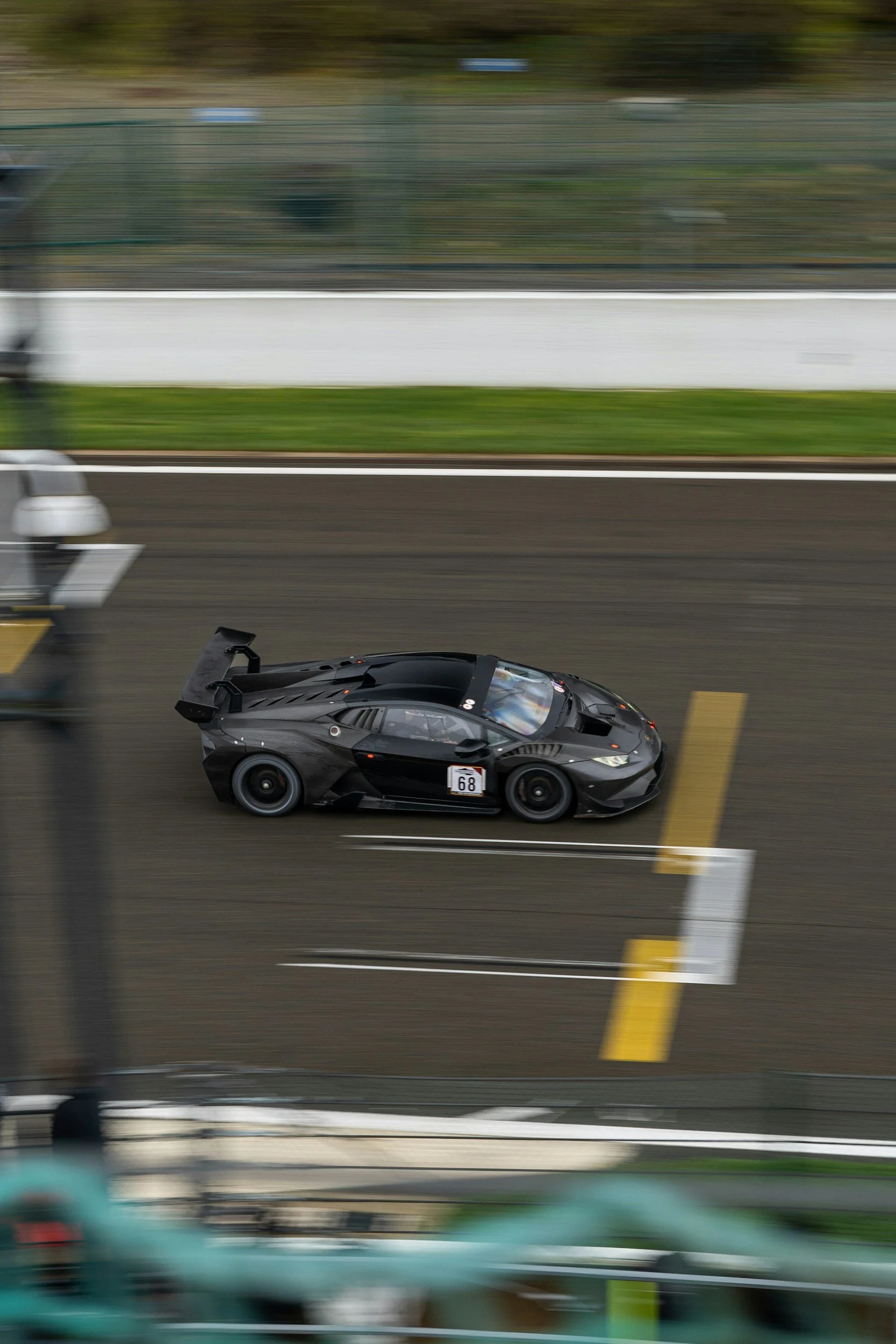 A black sports car racing on a track, captured from above with motion blur.