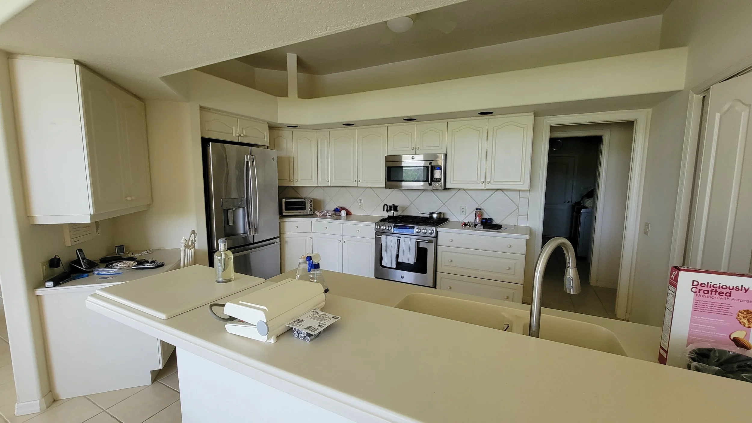 Dated kitchen with worn countertops and a basic backsplash, in need of a family-friendly update.