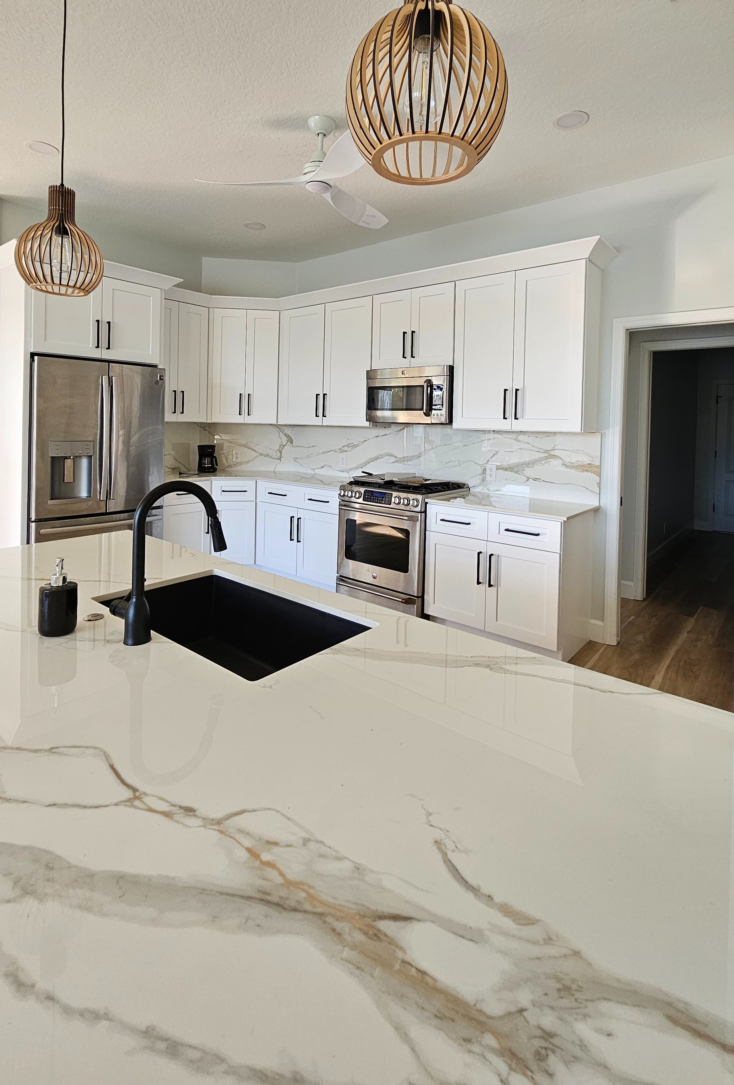 Transformed kitchen featuring elegant Calacatta Oro countertops, full-height backsplash, and modern black accents.