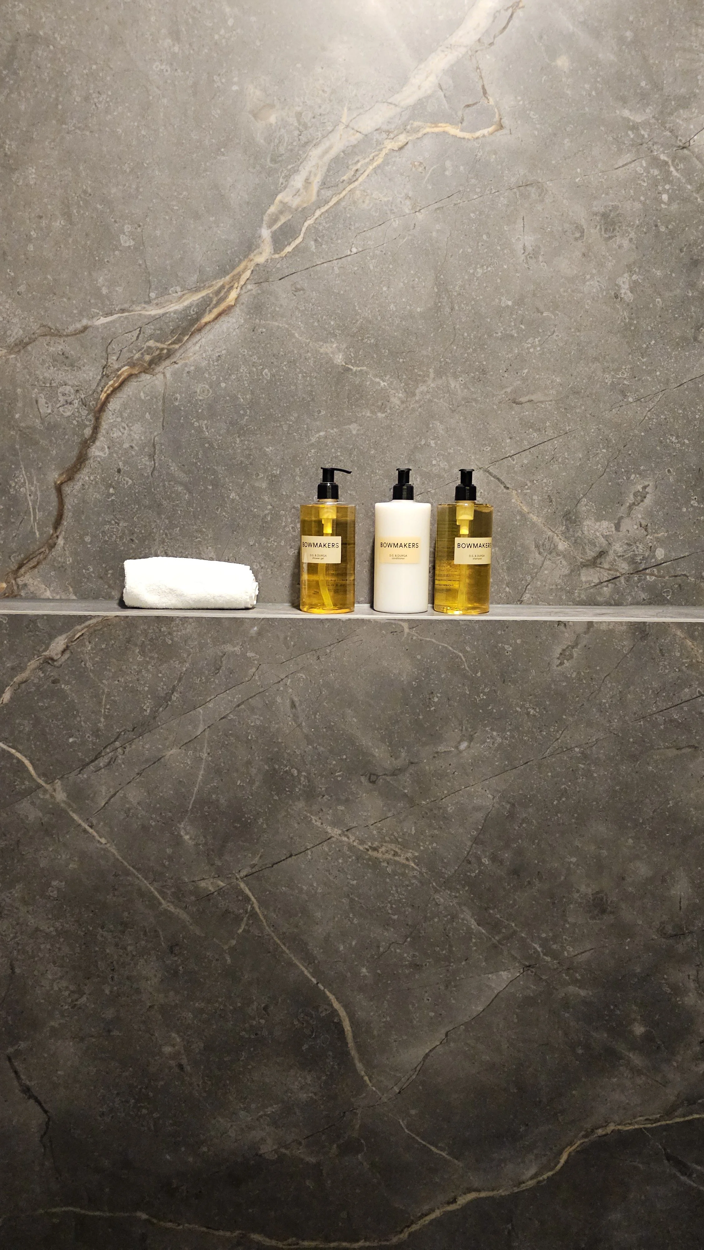 A luxury residential master bath featuring seamless full-height porcelain slab shower walls with continuous marble veining and zero grout lines.
