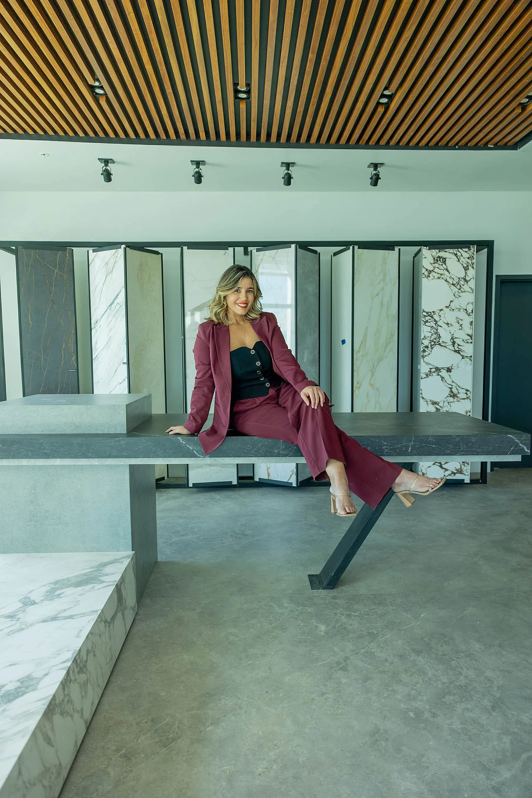 Mineral surface expert Lais Luz in a Florida stone showroom surrounded by premium large-format porcelain panels for vertical wall applications.
