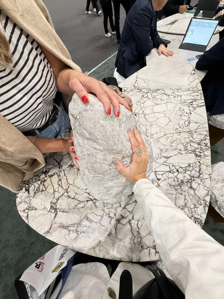 Lais Luz and Yasmin Furtado are handling a large piece of quartzite during coverings tile show.