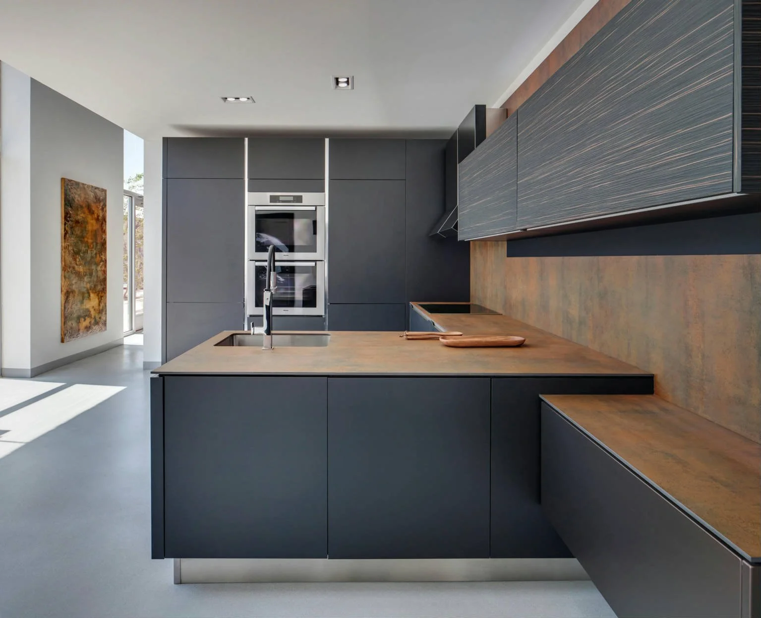 A high-end residential living space featuring a full-height porcelain slab backsplash wall with an oxidized iron-effect finish.