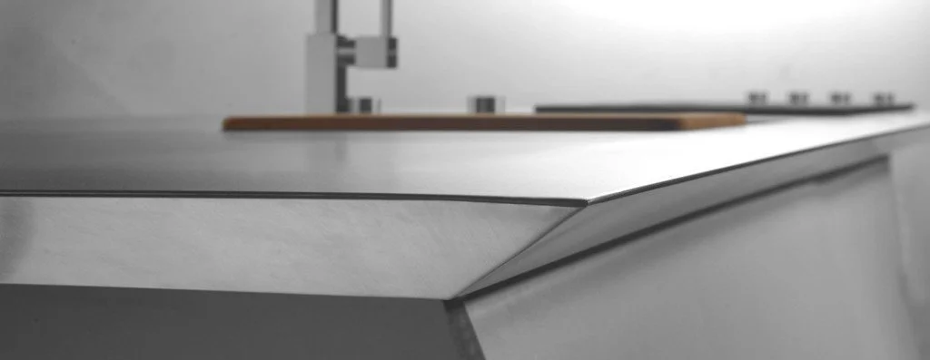 A close-up view of a porcelain slab sample featuring a custom-machined shark nose edge profile, highlighting the precise 45-degree reverse bevel undercut.