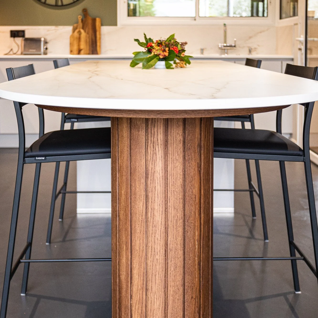 Oval Dekton table with a wood-grain pedestal base.