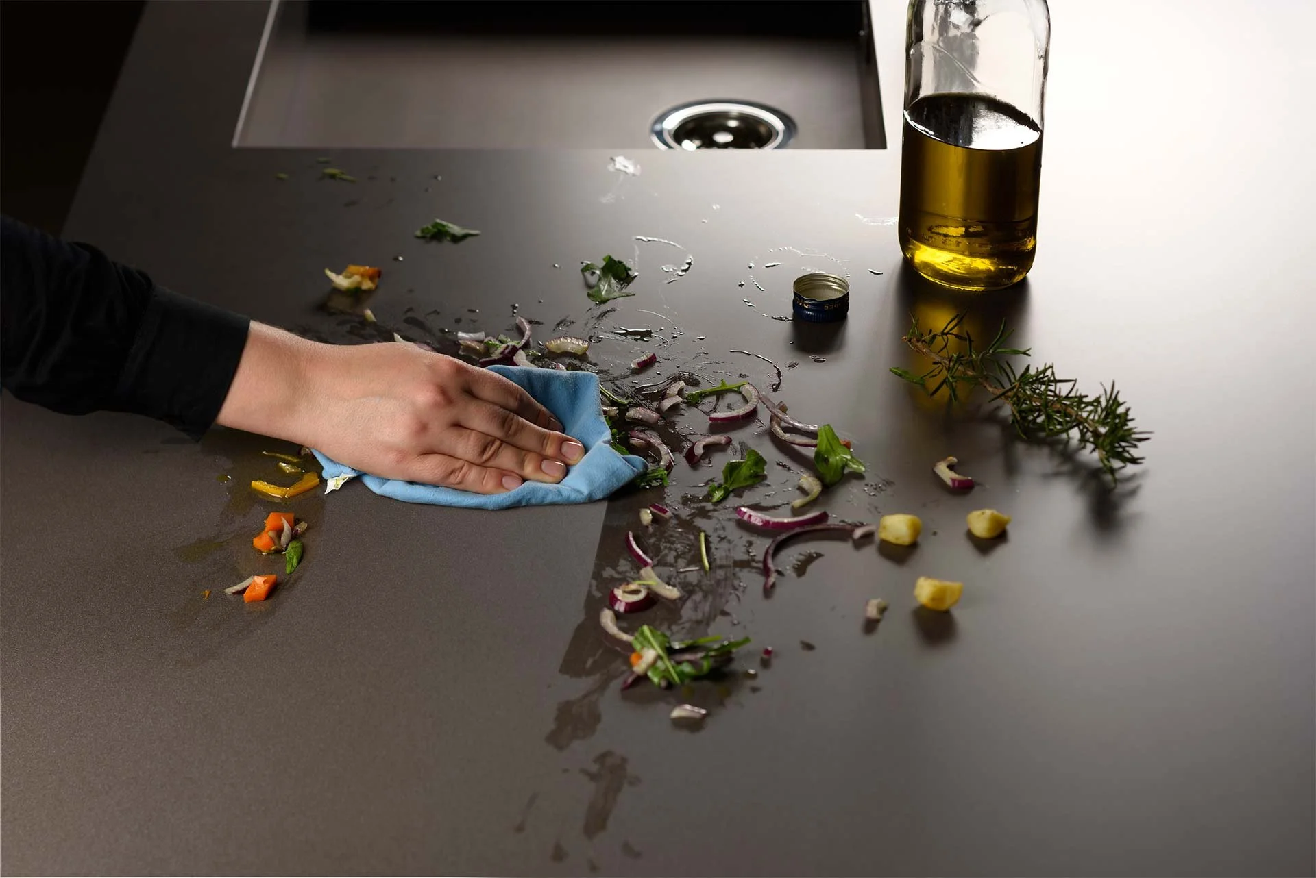 A person easily wiping down a dark Lapitec countertop, demonstrating the low-maintenance and stain-resistant properties of this silica-free mineral surface.