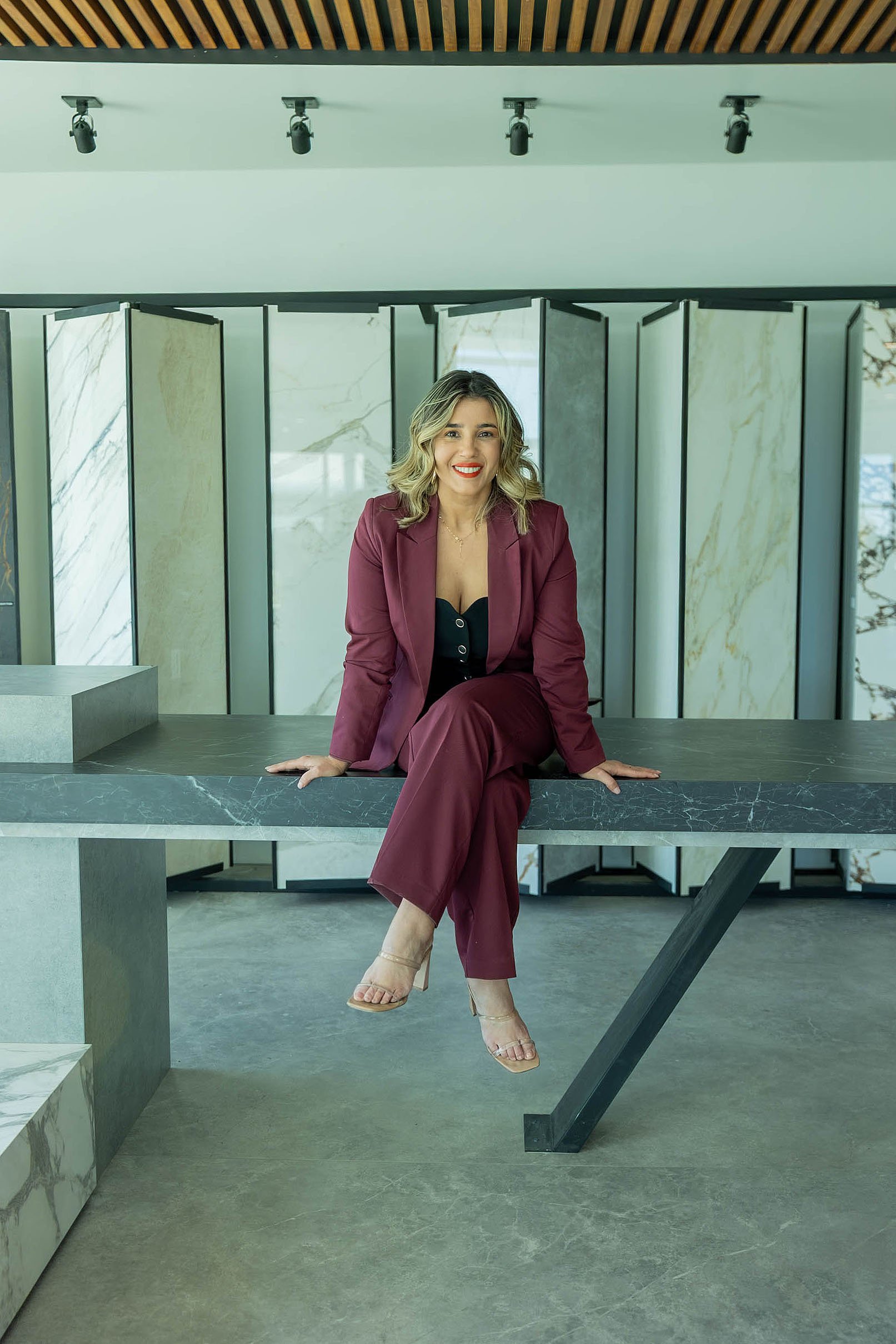 Lais Luz surface systems specialist in a showroom with porcelain slabs and Dekton-style architectural surfaces used for design and fabrication projects.