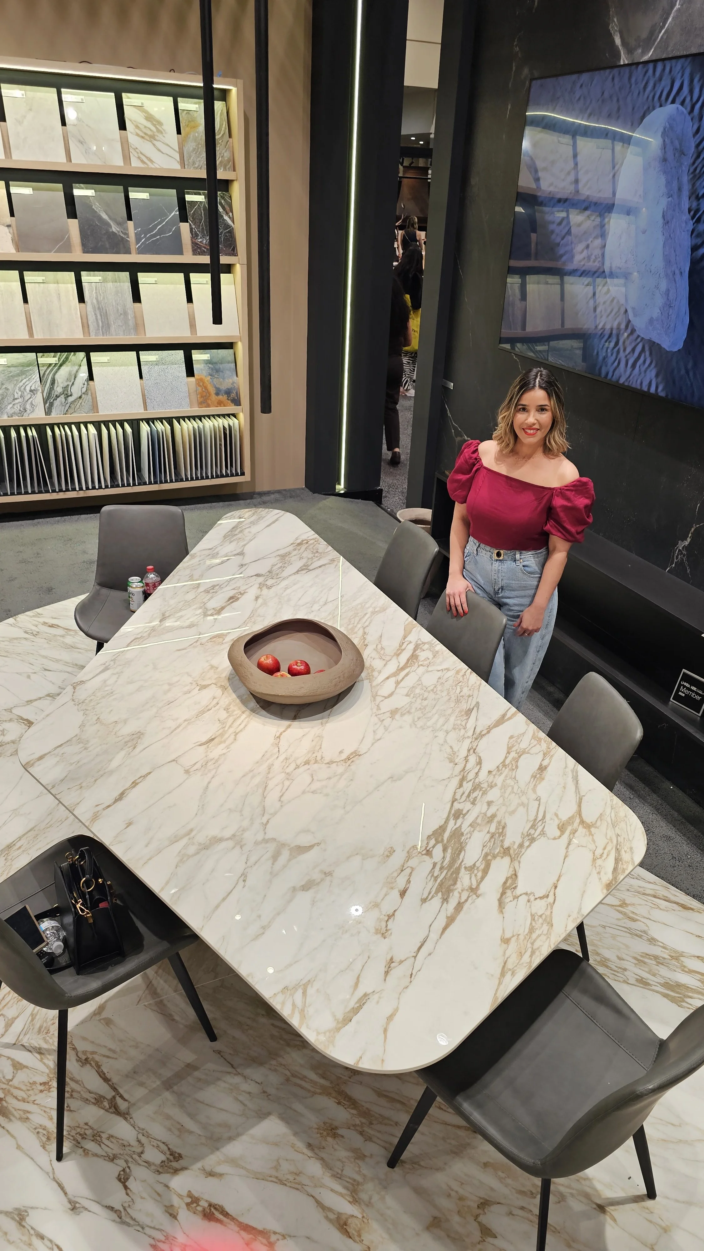 Lais Luz standing next to a custom white and gold marble-look Infinity Surfaces porcelain slab dining table supplied by UMI Stone.