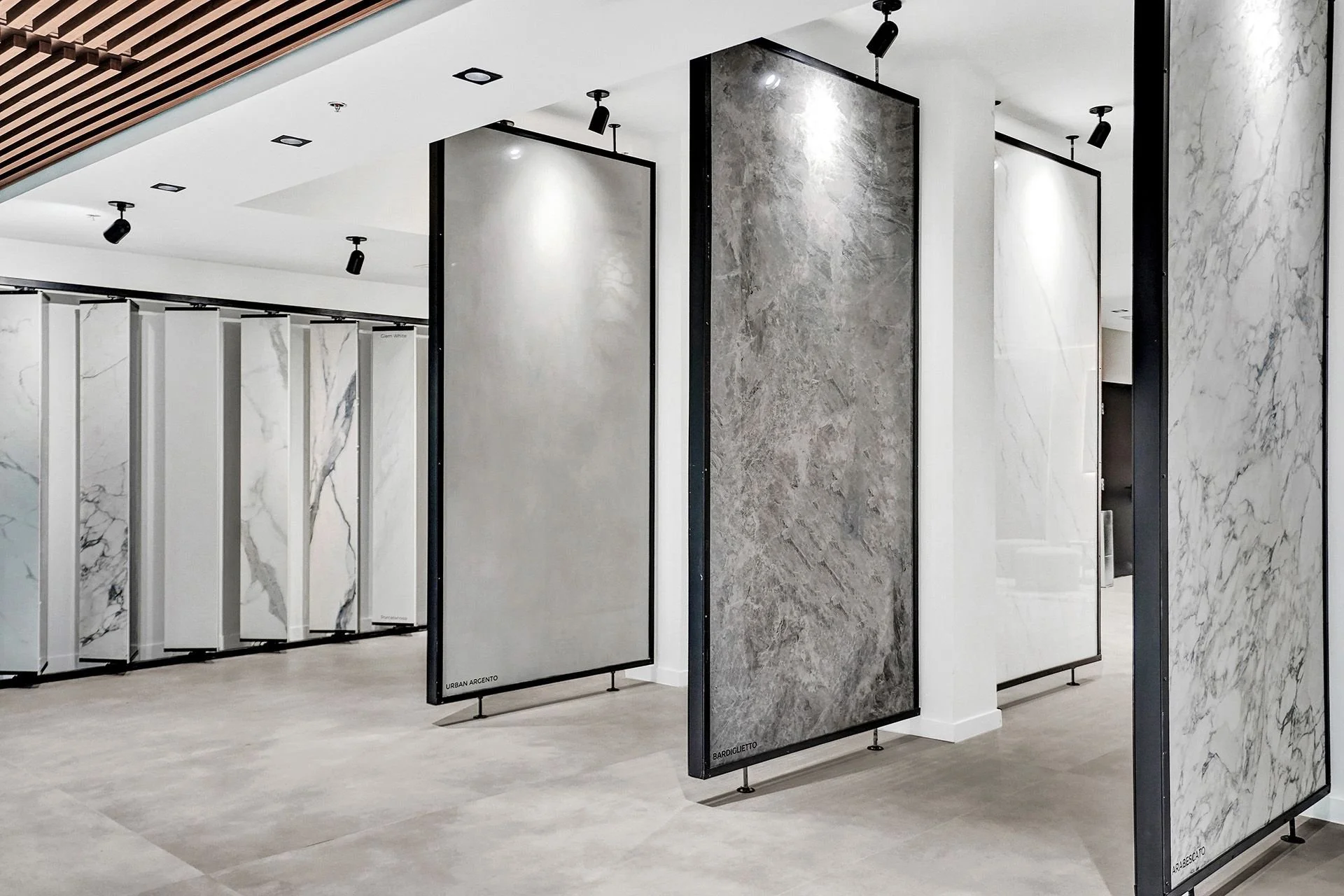 Modern Lais Luz Design showroom in Southwest Florida featuring large-format porcelain slabs on vertical display racks. Diverse selection of marble-look and stone-look porcelain colors.