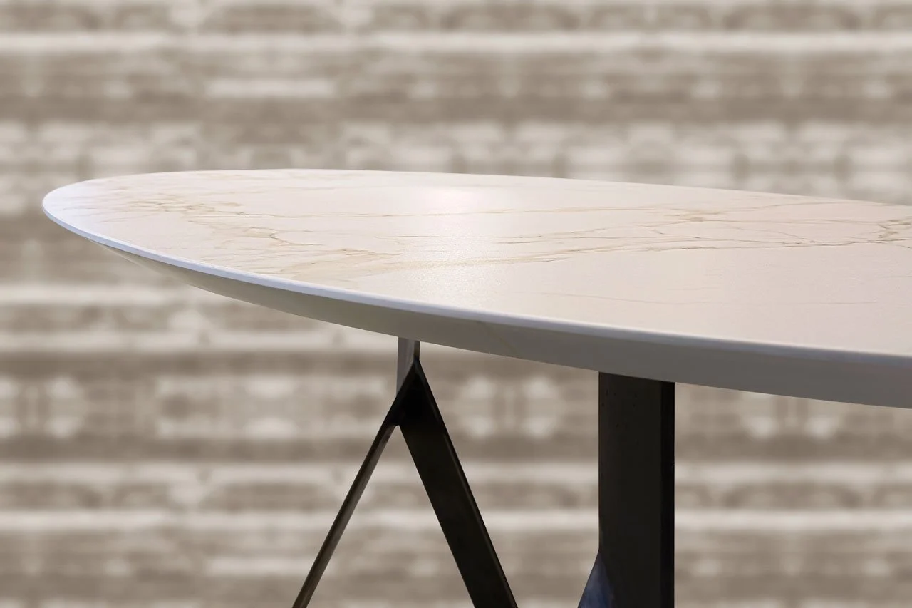 A shark-nose edge adds a touch of drama to this modern table, featuring a porcelain slab top with subtle veining.