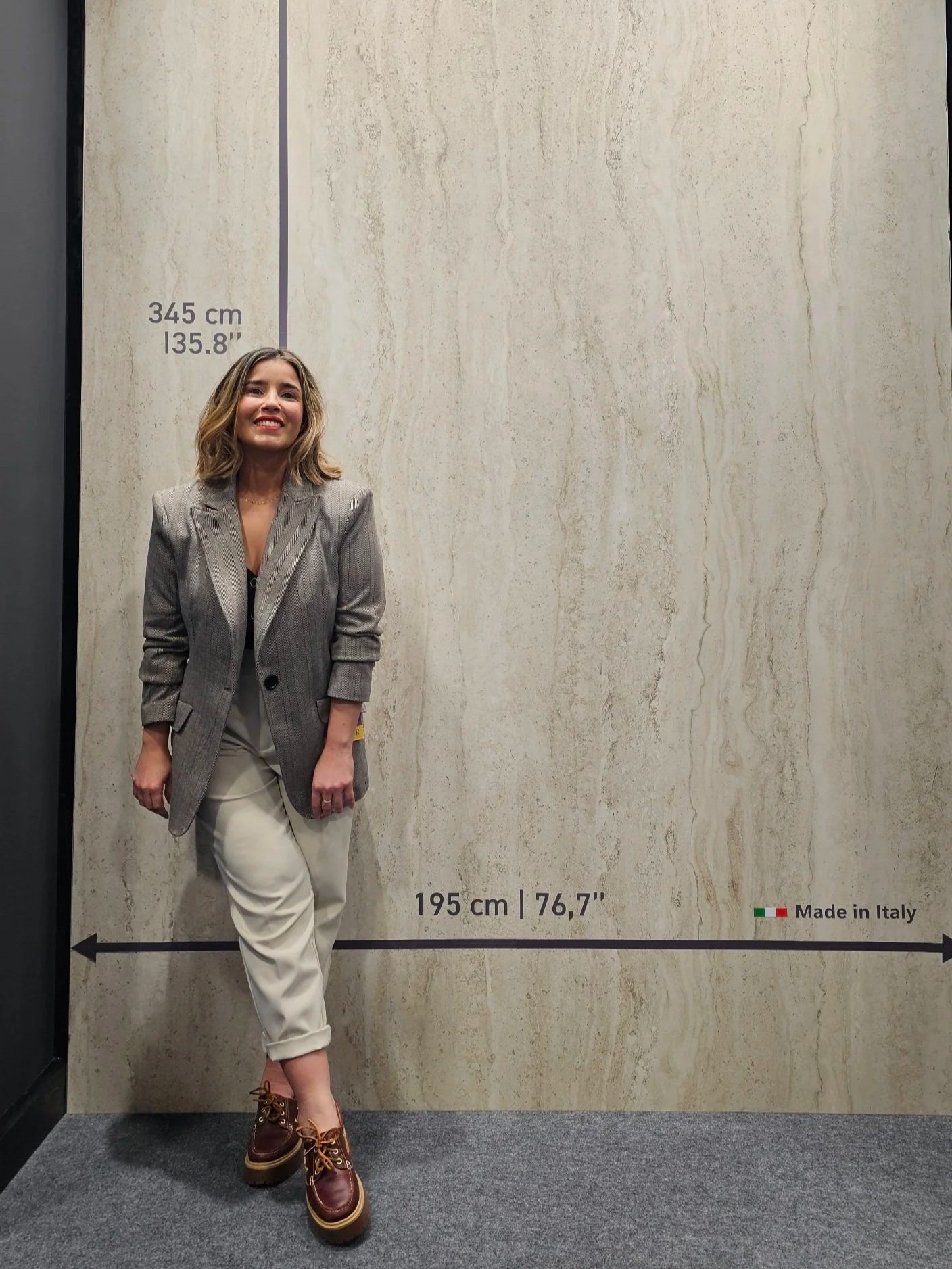 Lais Luz, Sarasota-based expert in 2cm porcelain and Dekton surfaces, standing with a large-format Italian porcelain slab for outdoor kitchen applications.