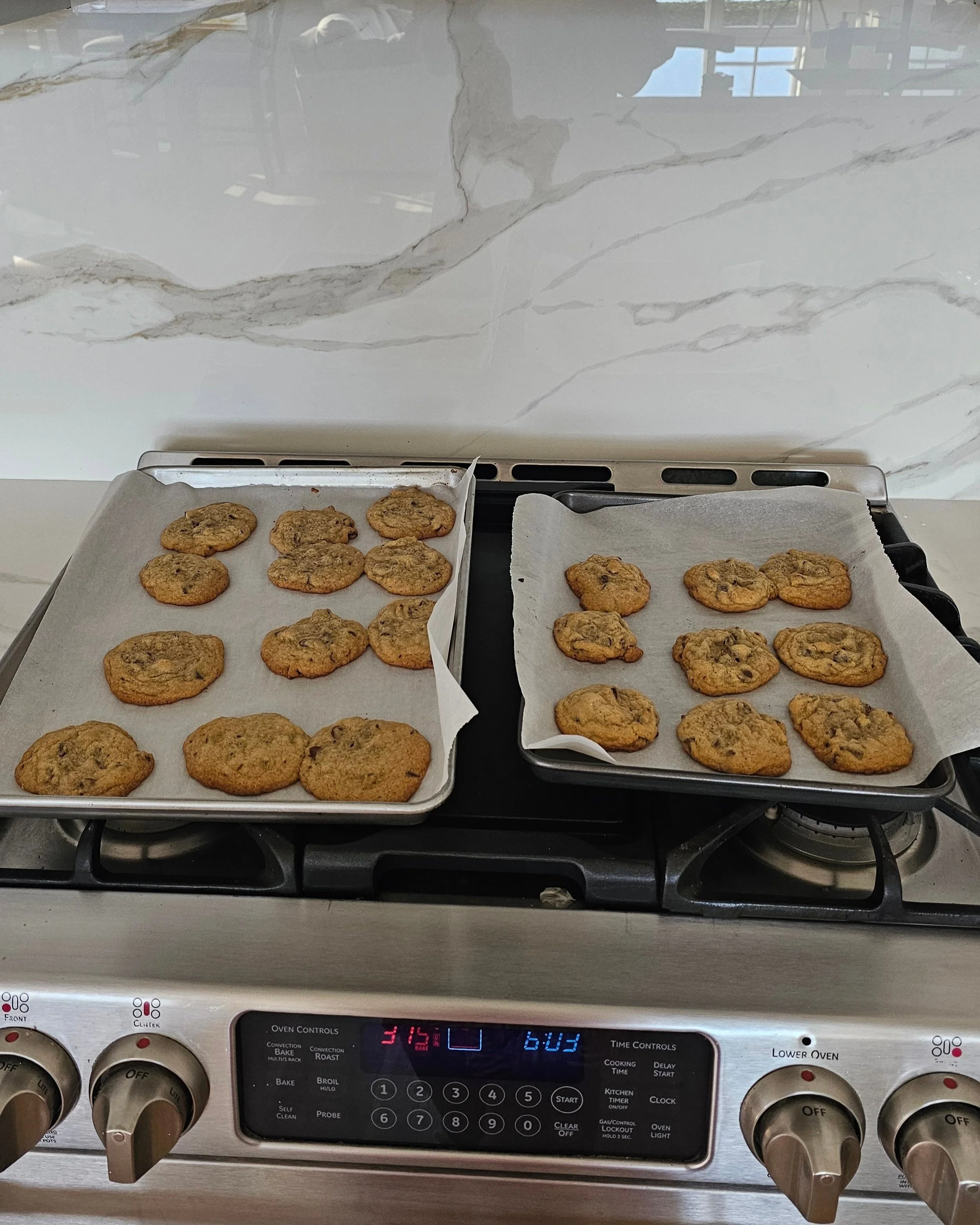 Freshly baked cookies cooling on a Calacatta Oro countertop, showcasing its heat resistance and durability for everyday kitchen adventures, just like grandma's baking.