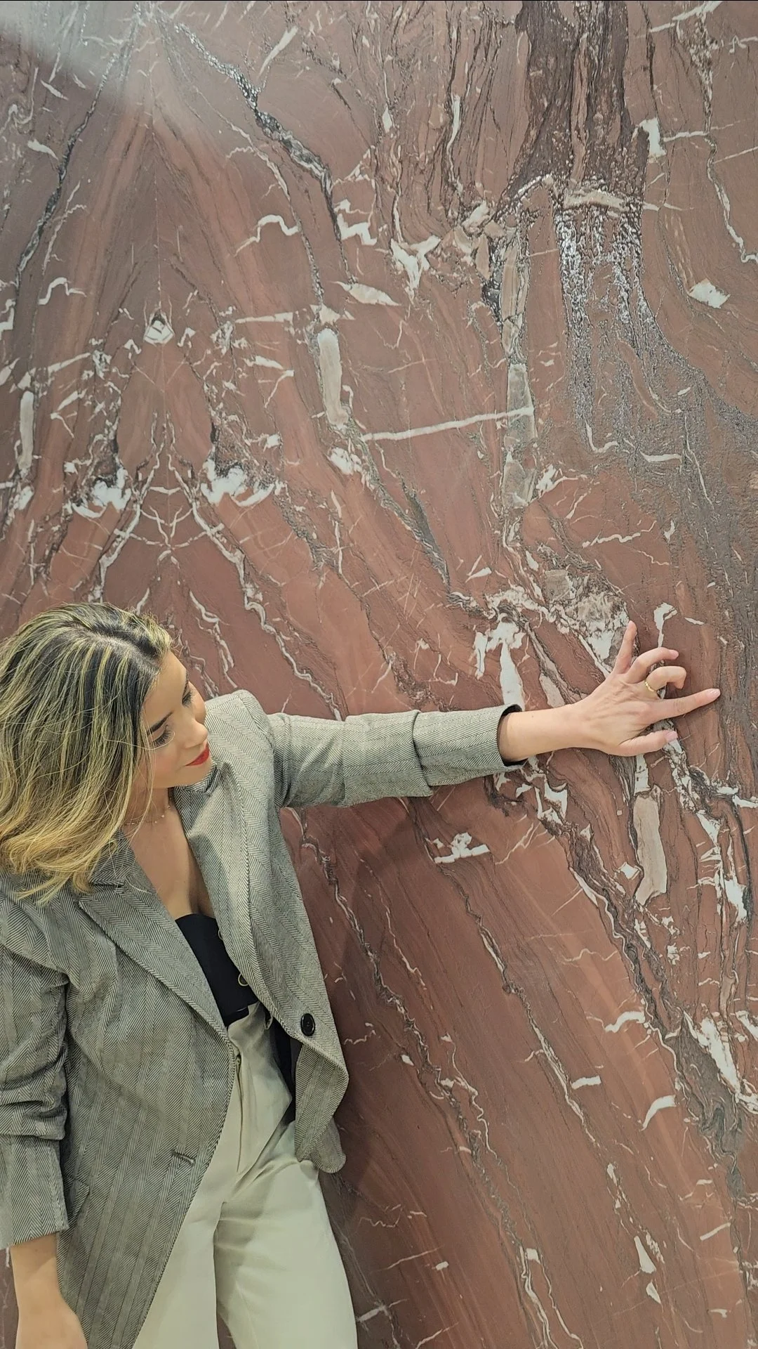 Lais Luz examining a large-format red marble slab for a high-end interior design project.