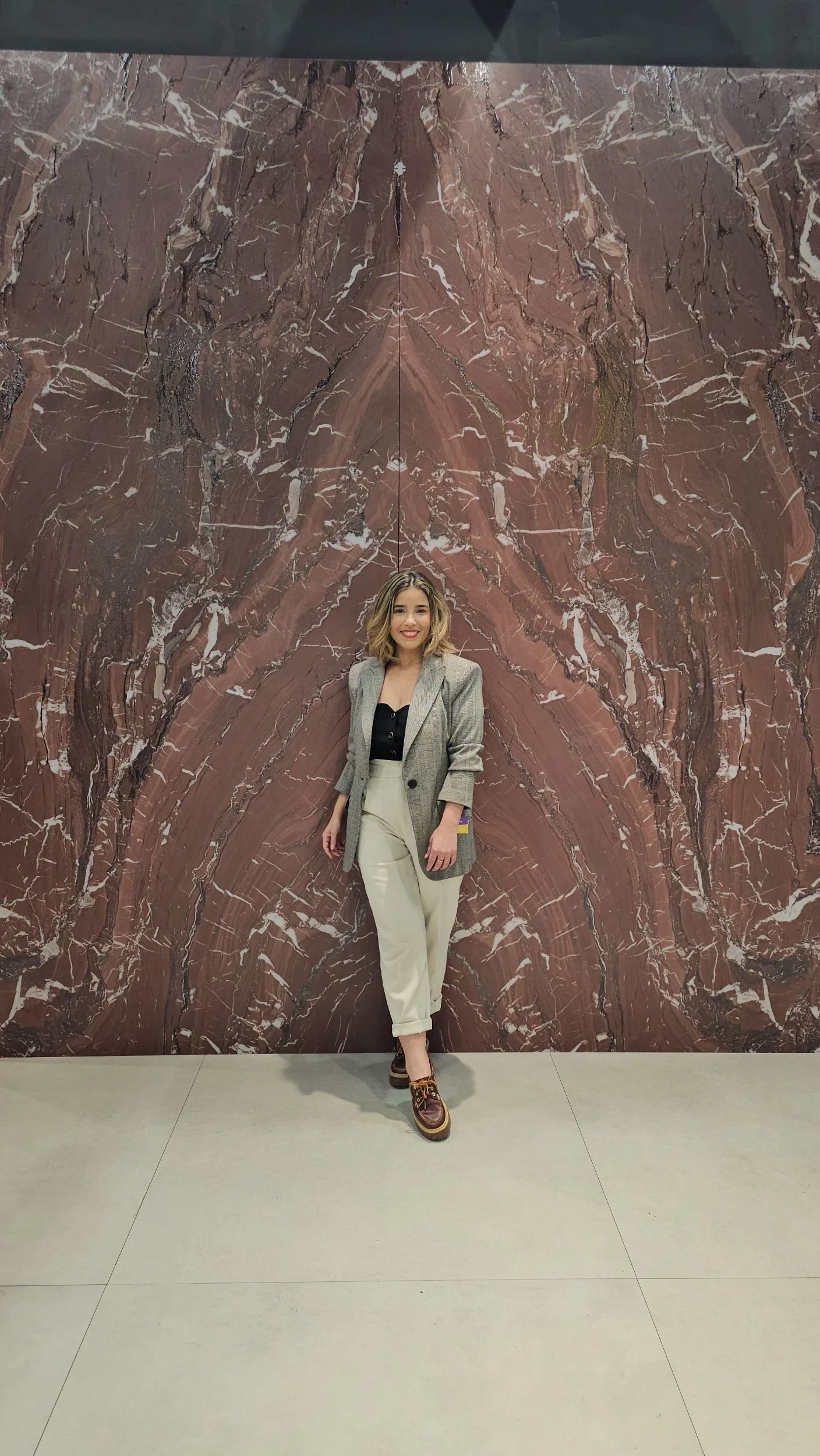 Lais Luz standing next to a large porcelain slab accent wall Kutahya Booth at the Coverings trade show.